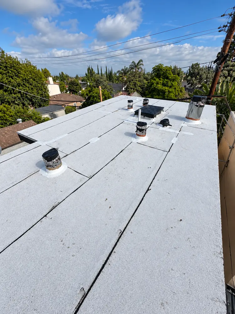 Finished white cap sheet on an ADU flat roof with every vent flashed and sealed