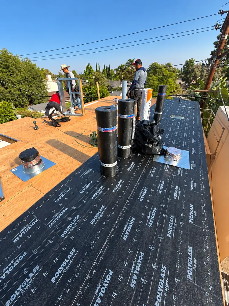 Crew rolling out Polyglass underlayment on a new ADU flat roof