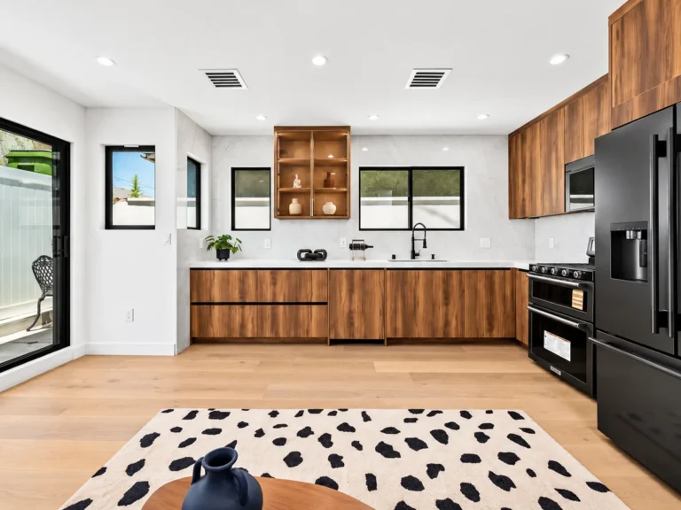 Kitchen inside a Rancho Park ADU built by MAMOS, wood-grain cabinets and black appliances