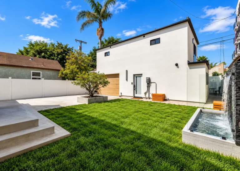 Backyard ADU in Rancho Park built by MAMOS, white stucco with a lawn and a water wall